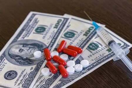 Money and pills with drugs and a syringe