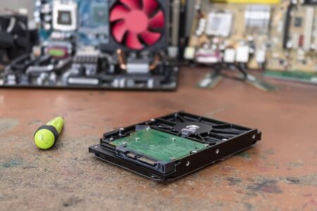 A broken and dusty computer hard drive lies on a table in a repair shop