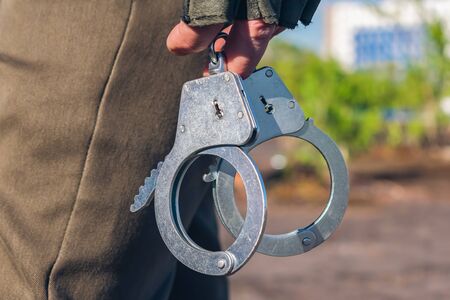 Handcuffs in the hands of a policeman close-up. Police equipment partの写真素材