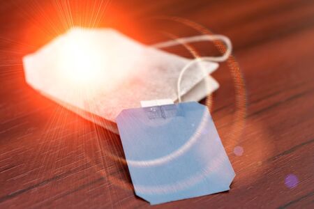 A tea bag with a label lies on a table in sun glareの写真素材