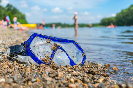 Scuba diving goggles covered with sand lie abandoned on the seashoreの写真素材