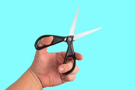 Hairdresser holding scissors for cutting hair or nails on blue backgroundの写真素材