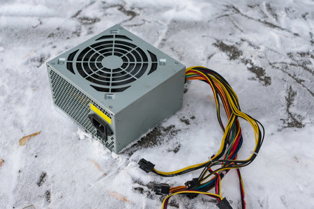 An old computer power supply discarded in the snow in winter