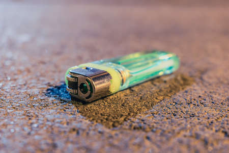 A used and discarded lighter lies on the road in the eveningの写真素材