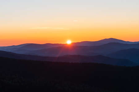 Beautiful and bright sunrise in the mountains. The sun's rays are breaking through from the tops of...