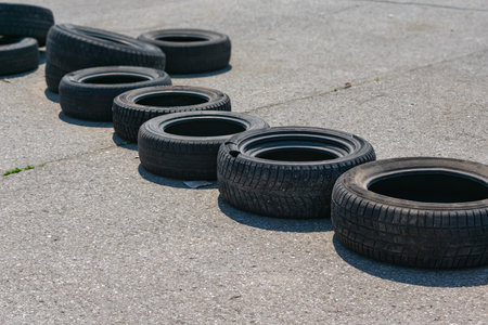Old car tires lie on the asphalt in the form of a blockage on the race track