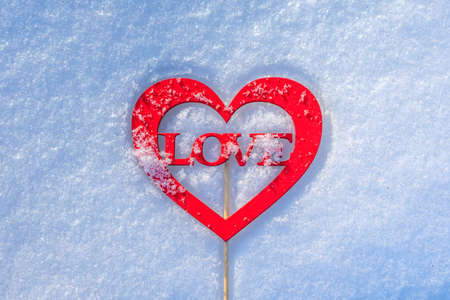 A heart-shaped figure with the word love lies on the snow. Love message in romantic formの写真素材