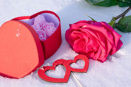Romantic composition with a rose, a box of chocolates and a love message on the snowの写真素材
