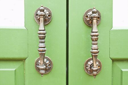 Door handles with an old double wood door painted with green.の写真素材