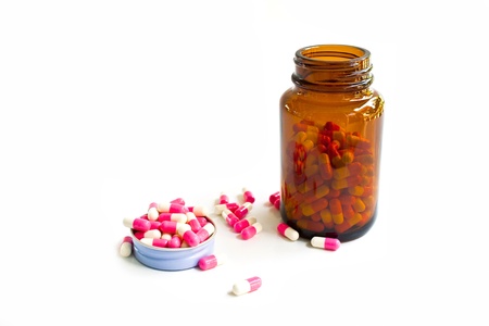Pills spilling out of pill bottle isolated on whiteの写真素材