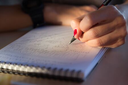 Hand with red nail hold pencil sketching paper works with sunlightの写真素材