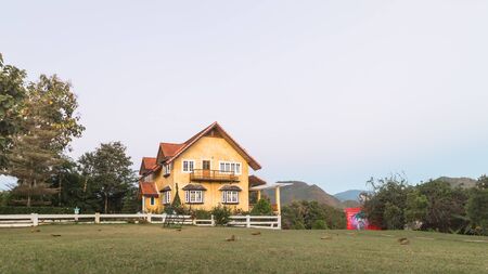 Yellow house with big grass field during time before sunsetの写真素材