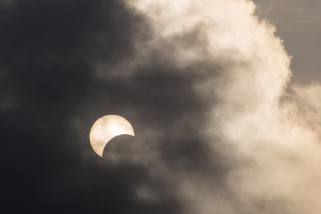 Partial sun eclipse around 41 percent behind dark cloude in Bangkok, Thailand on 9 March 2016.