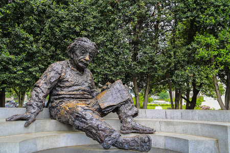 Washington DC, USA - May 16, 2014: Iron statue of Albert Einstein reading a book who sit on a flat stairs with trees as a backgroundのeditorial素材