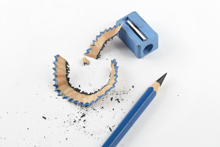 Close focus on sharpen blue pencil beside pencil sharpener and shavings on white paperの写真素材