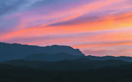 Black silhouette mountain with sweet colorful sky after sunset in winter season. の写真素材