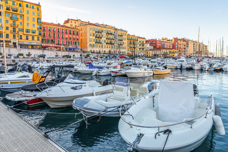 Nice, France - October 2, 2018: Morning scene of fishing boats parking at port near colorful buildings inside bay area at Nice, France.のeditorial素材