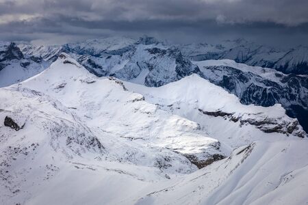 Mountains around top of Shilthorn, Switzerland covered by snow with overcast sky in winter.の写真素材