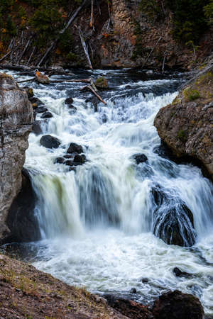 Blurry motion of flowing water of waterfall over black rock river.の写真素材