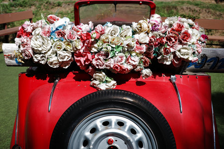 Classic old style of unuse red car and hanging black tire wheel on back decorated by bunch of fake...