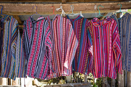Colorful mountaineer shirts in blue and red hanging on wooden rack of rural garment store.の写真素材