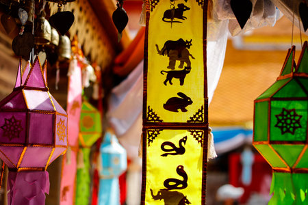 Chiangmai, Thailand - January 1, 2022: Vertical yellow flag with stickers of animals based on zodiac birth year which decorated with colorful lamps inside Thai temple.のeditorial素材