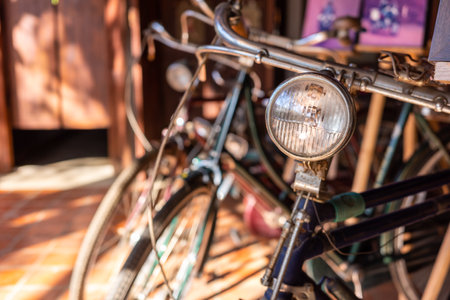 Close up on bike headlight with blurry background of other vintage and old bikes inside antique shop.の写真素材