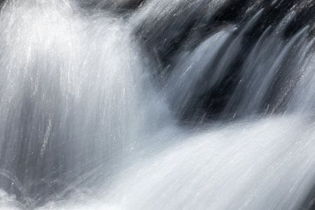 Long exposure of flowing water in natural stream with dark background.