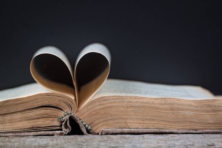 An old book with heart-shaped pages, dark background.の写真素材