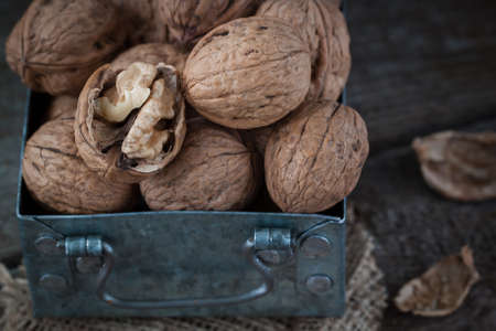 Walnuts in a small iron box and a canvas napkin. Wooden background.