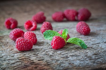Raspberries with a mint leaf on the wooden background. Closeup.