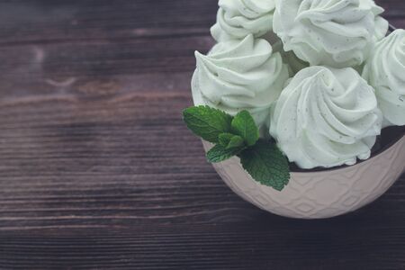 Mint Marshmallow or zephyr in the bowl with a leaf of mint on the wooden background. Toned