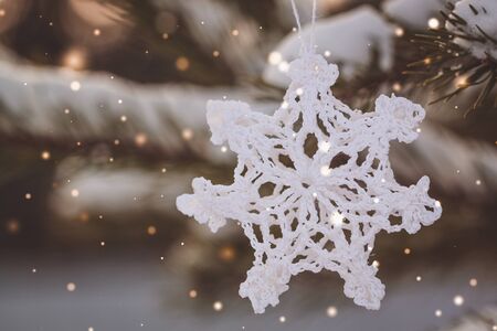 Christmas white vintage crocheted snowflake on the branches of a snowy tree. Toned. Fairy effect.の写真素材