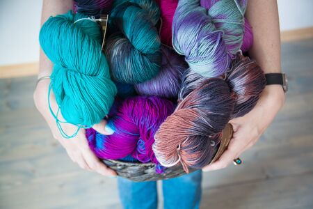 Colourful yarn balls in the basket on the wooden background. Toned.