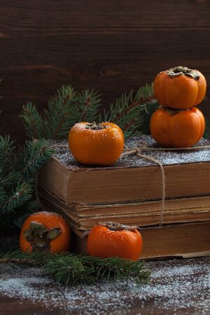 Persimmon on the pack of old books on the wooden background. Toned.の写真素材