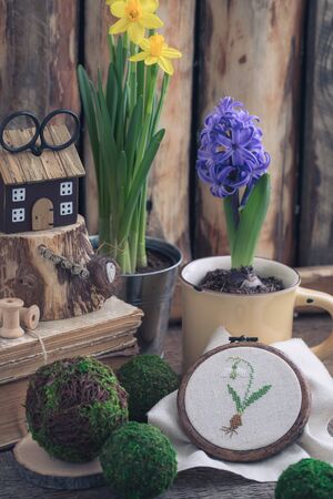 Spring flowers yellow narcissus and blue hyacinth with cross stitched snowdrop on the wooden background. Easter and March 8 postcard concept.Toned.の写真素材