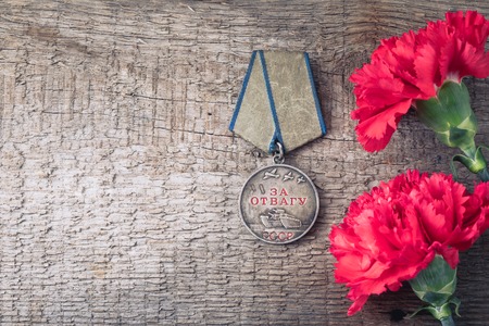 The Old Soviet Medal For Bravery of the Second World War with a red carnation, Victory Day May 9 postcard concept, toned vintageの写真素材