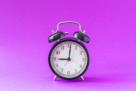 Black modern alarm clock set at nine o'clock, isolated, work school begins concept, ultraviolet background, tonedの写真素材