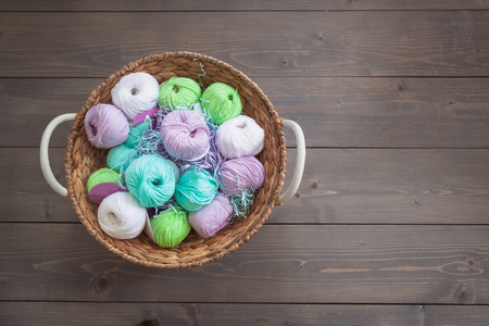 Colorful balls of wool yarn in a basket on the rustic background, with a copyspaceの写真素材