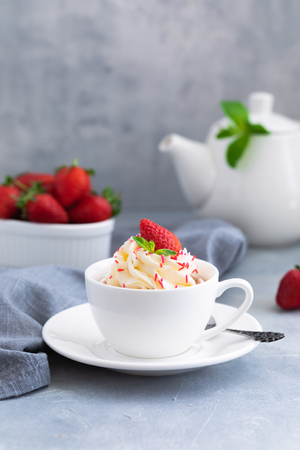 Homemade muffins or cupcakes with vanilla cream and fresh strawberries on the light grey background, with a copyspaceの写真素材