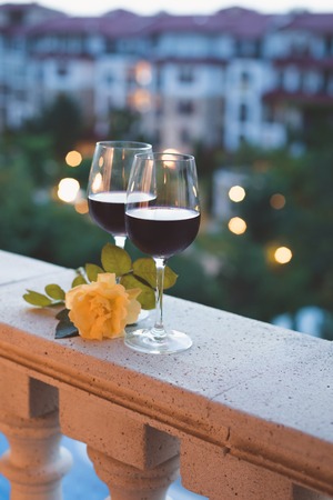 A glass of red wine on the balcony, summer swimming pool backgroundの写真素材