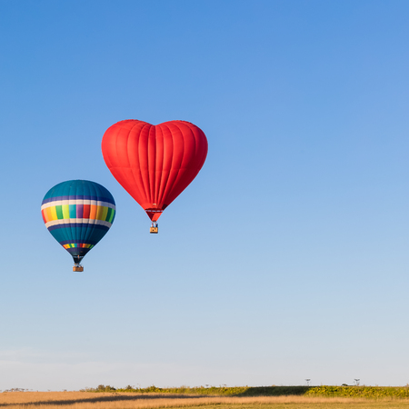 Red heart shaped and colourful air balloon flying in the sky, tonedの写真素材