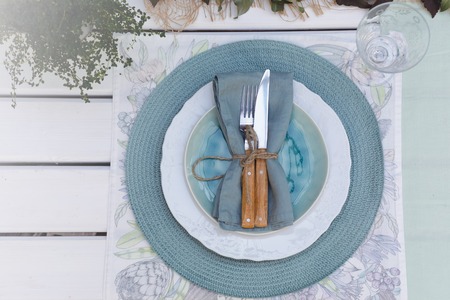Holiday Summer or early autumn outside table setting with linen napkins and green leaves, toned