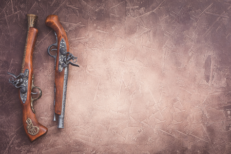 Two vintage pistols on wooden background, toned