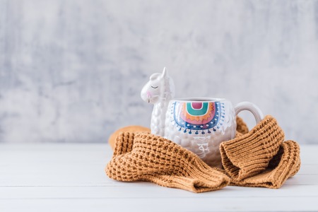 Colorful Llama shaped mug with knitted pullover on the white wooden table, tonedの写真素材