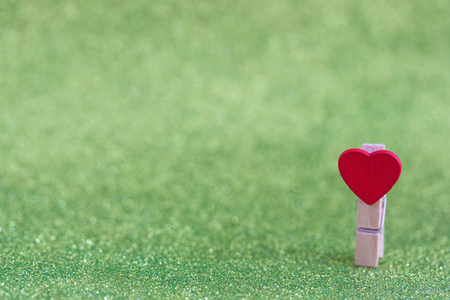 Small red wooden heart on light green sparkling background, with a copyspaceの写真素材