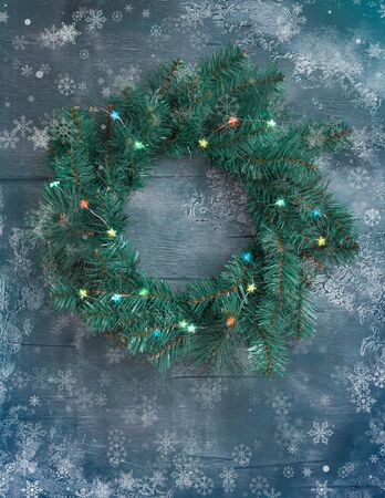 Christmas door wreath made of green tree fir branches and light garlands on dark grey wooden background, tonedの写真素材