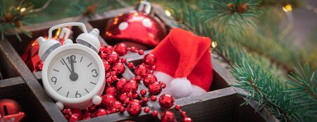 Christmas red and white glass toys, alarm clock, santa claus hat in the basket with fir tree...