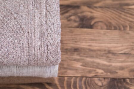 Stack of cozy knitted sweaters on a wooden table. Retro style. Warm concept, toned, Christmas...