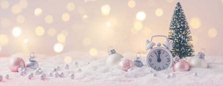 Pink and White glass Christmas balls with an alarm clock on a snowflake background, toned, postcard conceptの写真素材